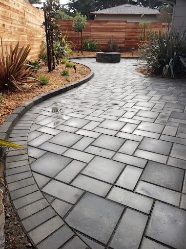 Curved paver path leading to a backyard fire pit
